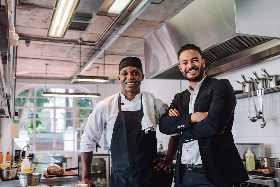 Specialized Business Insurance - Portrait of a Restaurant Owner and Head Chef Standing in a the Kitchen of Their New Restaurant